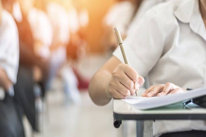 Exam withh school student having a educational test, thinking hard, writing answer in classroom for university education admission and world literacy day concept
