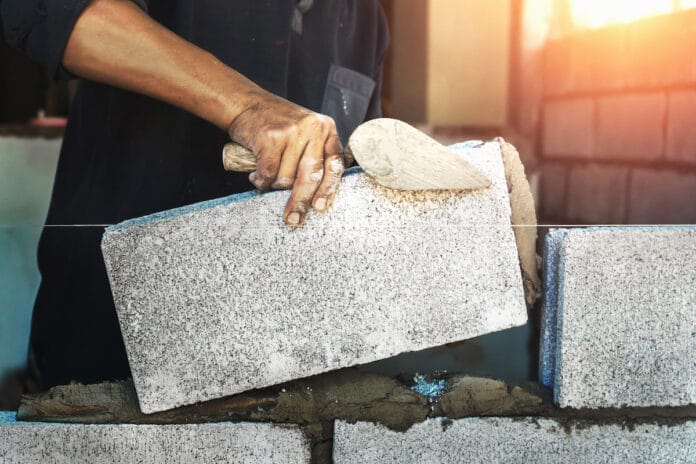 Worker building wall bricks with cement